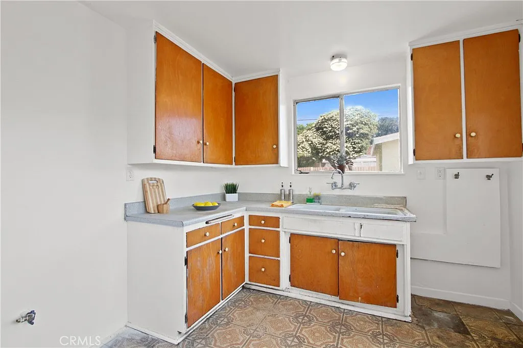 Kitchen with white and wooden cabinets, a window above the sink, and a patterned floor.
