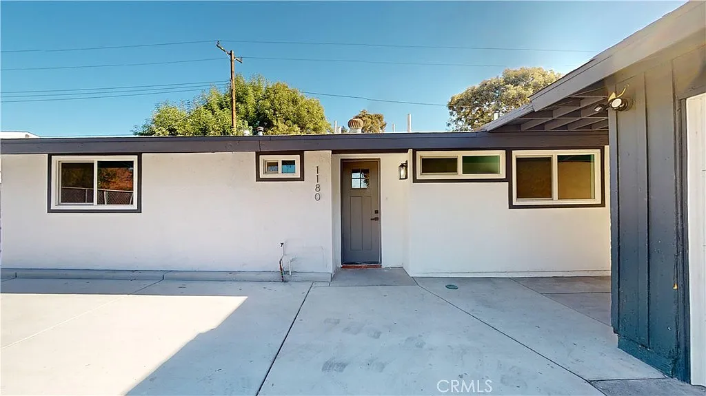 A single-story house with gray and white walls, a front door, windows and driveway,