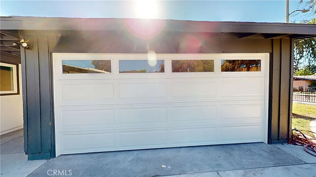 A white garage door with four windows on a dark-colored building.