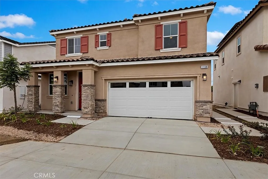 Two-story house real estate with brown walls, red shutters, garage, driveway, and plants.