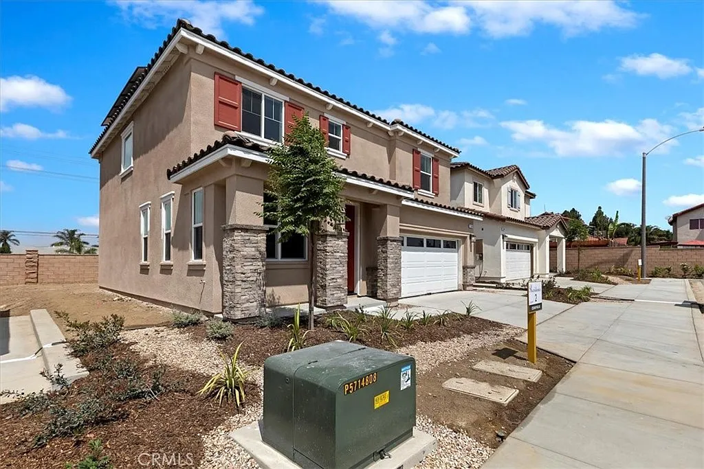 Two-story house real estate with stone front, red shutters, gravel yard, and plants.