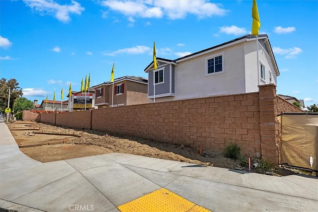 Construction site with wall and yellow flags on new homes.