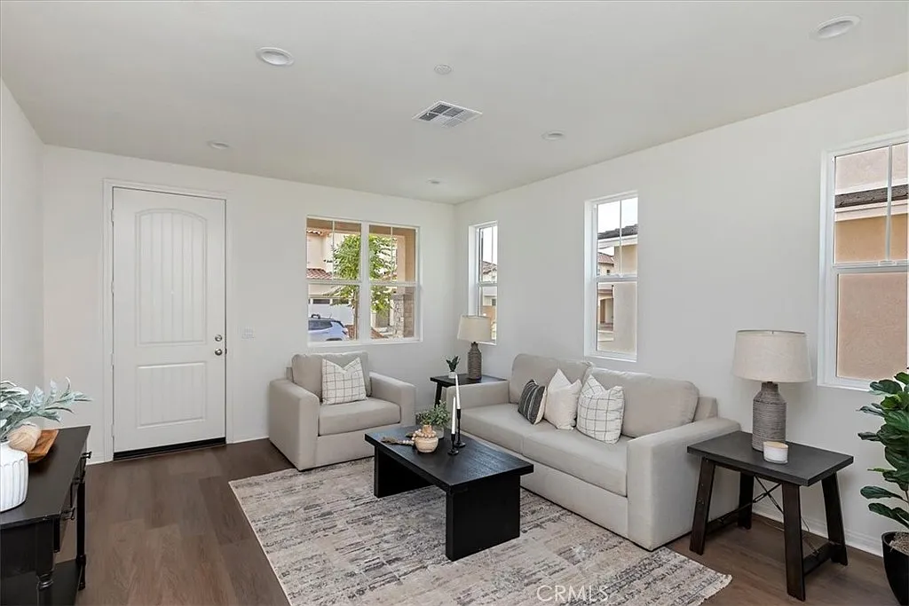 Living room with light gray sofa, black coffee table, potted plants, and windows letting in natural light.