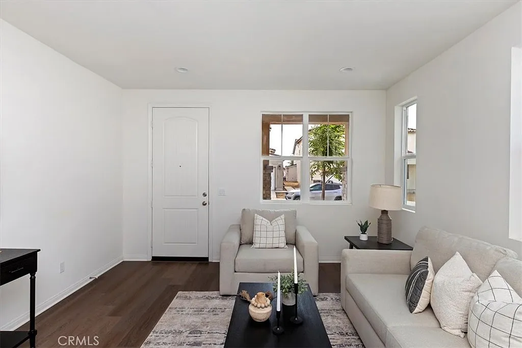 Living room with light sofa, decorative pillows, black table, window, and wood floor.