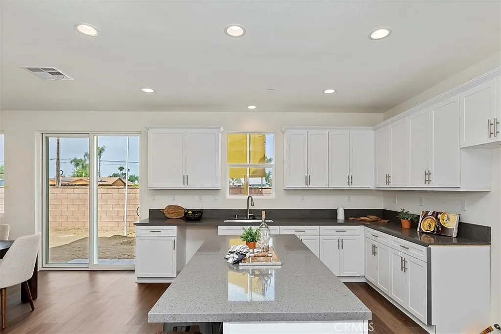 Kitchen with white cabinets, large island, stainless appliances, and sliding glass door to outdoor area.