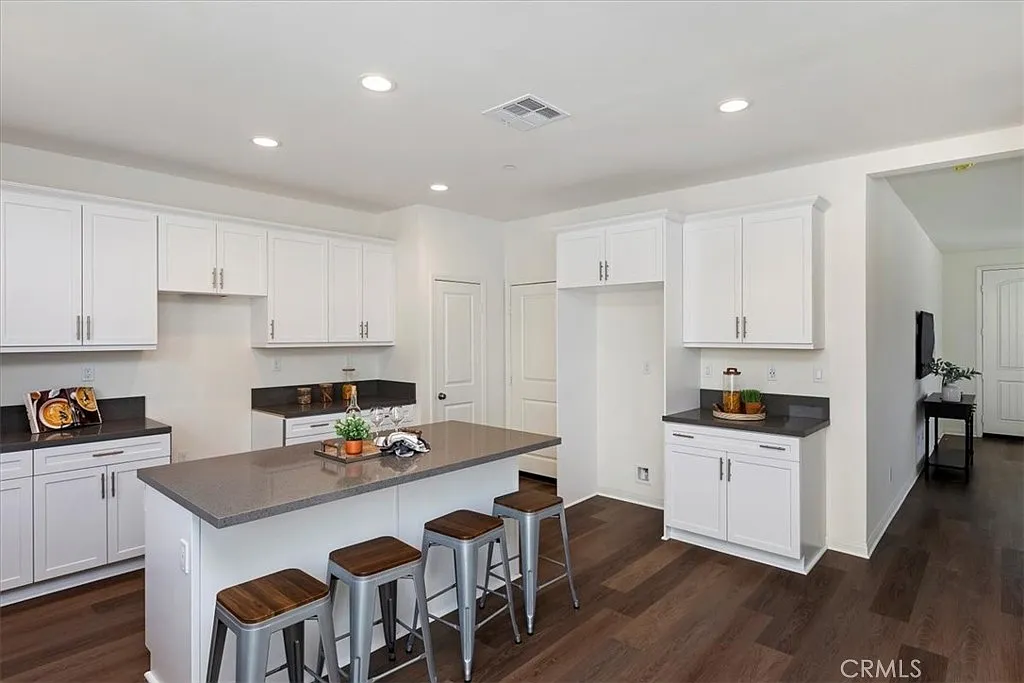 Kitchen with white cabinets, dark countertop, central island with bar stools