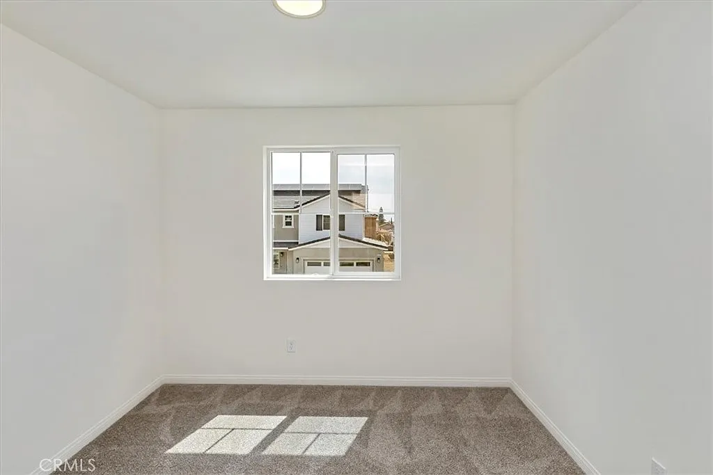 Vacant room with light walls, carpet floor, and a window