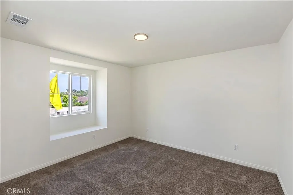 Empty room with light walls, brown carpet, and a window