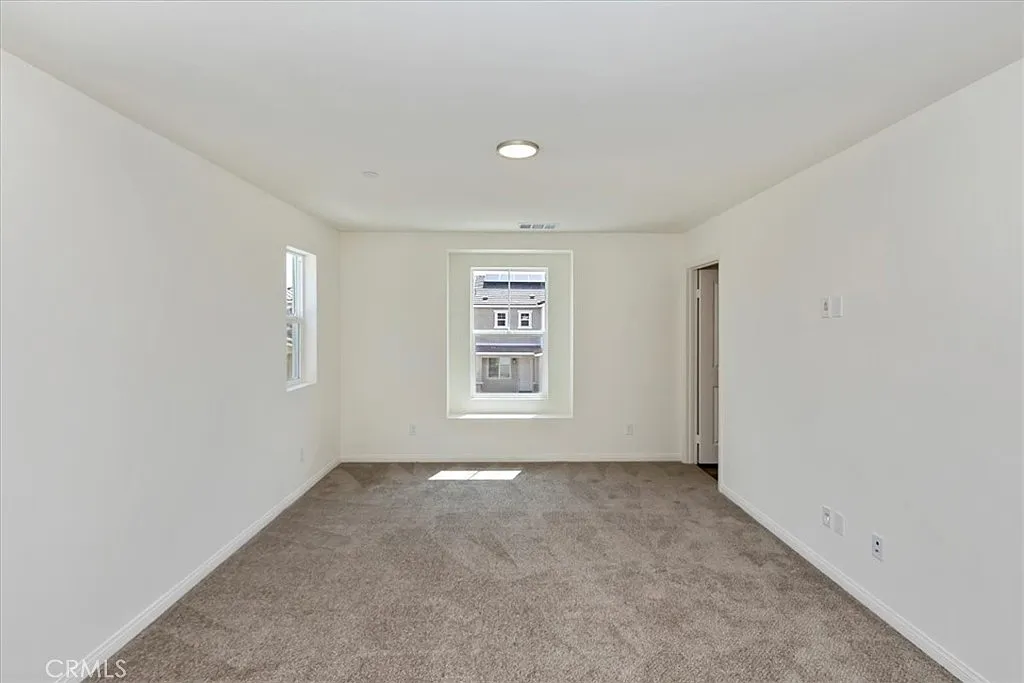 Vacant room with light walls, window, and carpeted floor.
