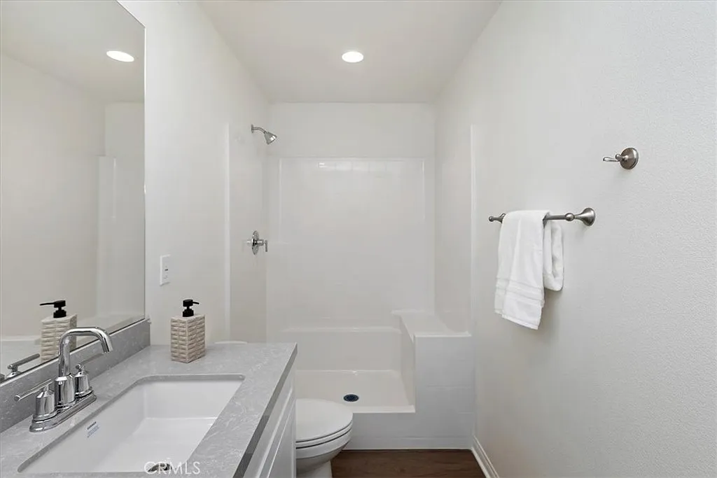 Bathroom with white tub shower, sink with mirror, towel bar, and neutral decor.