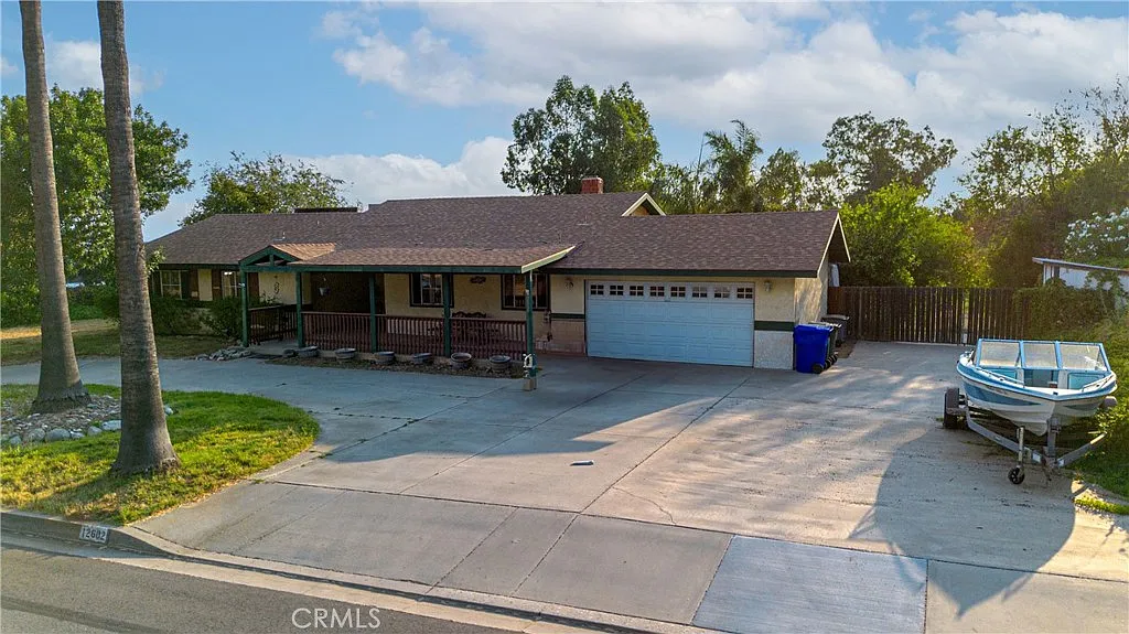 Single-story house real estate with brown roof, porch, garage, driveway, and boat.