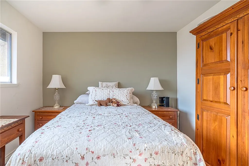 Bedroom with large bed, floral bedding, bedside lamps on wooden nightstands, and wooden wardrobe.