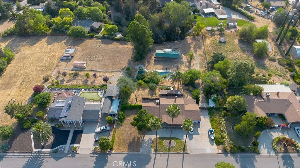Aerial view of suburban neighborhood with houses, open land, trees, and greenery, California real estate.