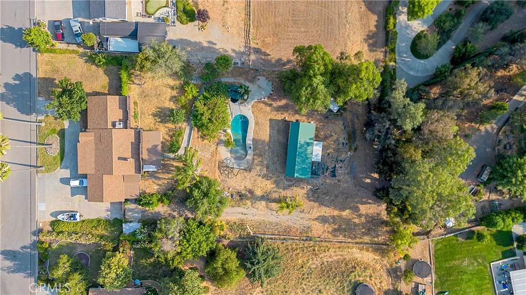 Aerial view of residential area with houses, swimming pool, and surrounding greenery, California real estate.