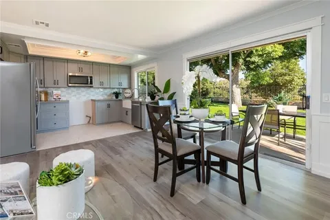 kitchen and dining area with glass table and chairs, gray cabinets, white countertops, and large windows showing garden outside
