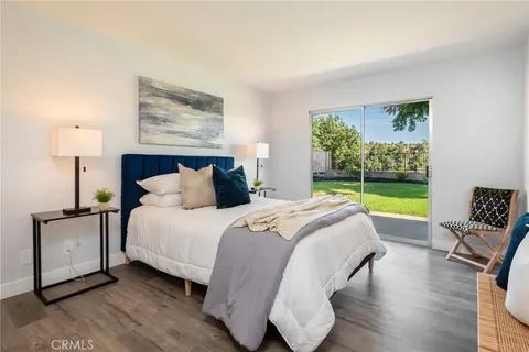 Bedroom with blue upholstered headboard, cozy bedding, and sliding glass doors to outdoor space with greenery