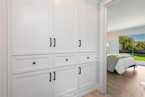 Bedroom with white built-in cabinets and large window showing outdoor space