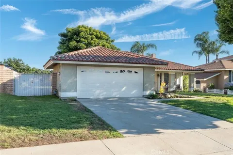 real estate house with tile roof, two-car garage, well-maintained lawn, and palm trees
