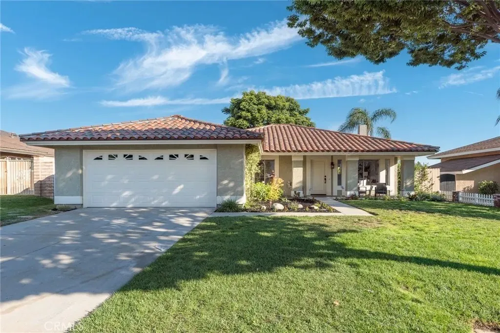Real estate house with tile roof, two-car garage, well-maintained lawn, and palm trees