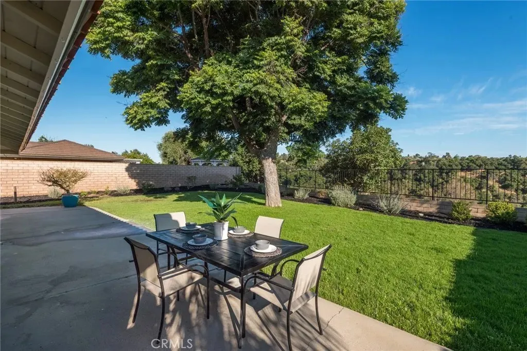 Patio with dining table, grass lawn, and trees around.
