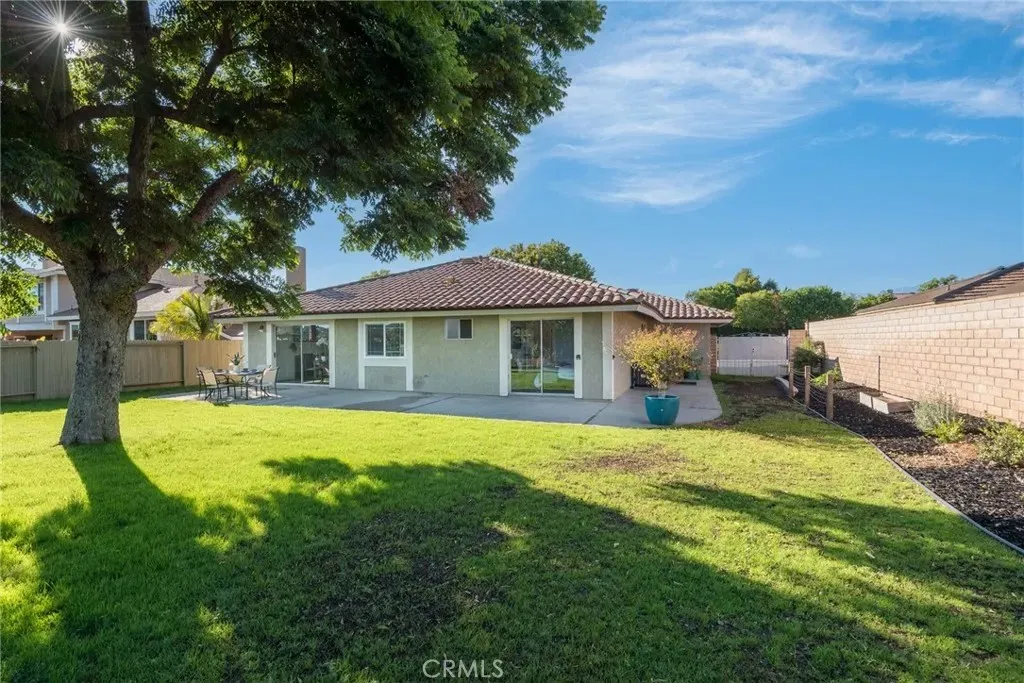 Single-story house real estate with tile roof, green lawn, and trees.