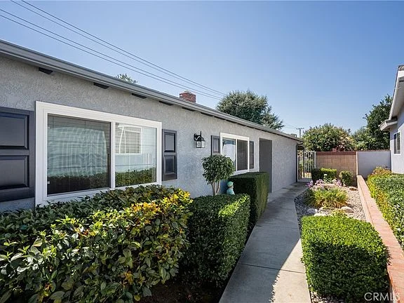 Pathway to California real estate house with trimmed hedges and landscaping
