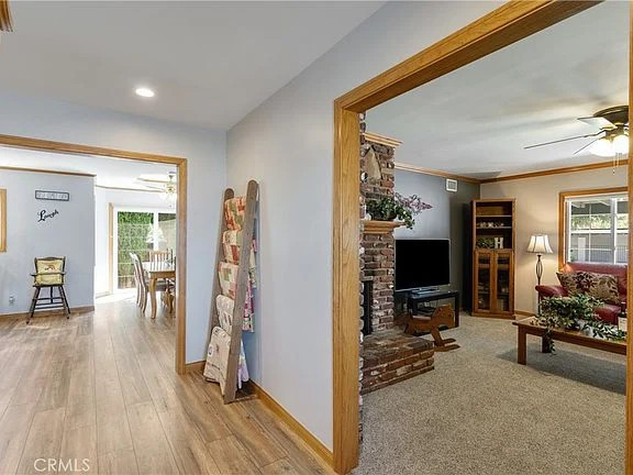 Home interior with hallway, wood trim, living room, dining area, and wooden floor