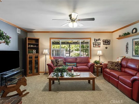 Living room with red leather sofa, wooden coffee table, TV, and large windows