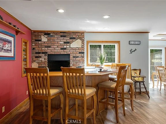 kitchen with circular bar, wooden stools, brick fireplace, and large windows