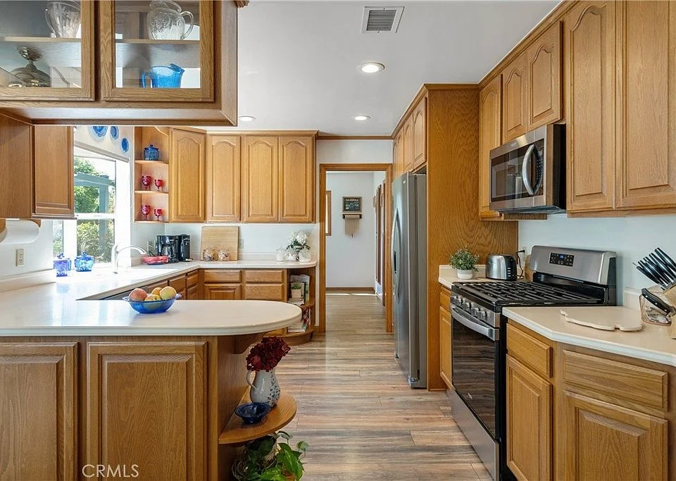 Kitchen with wooden cabinets, stainless steel appliances, central island, and window light