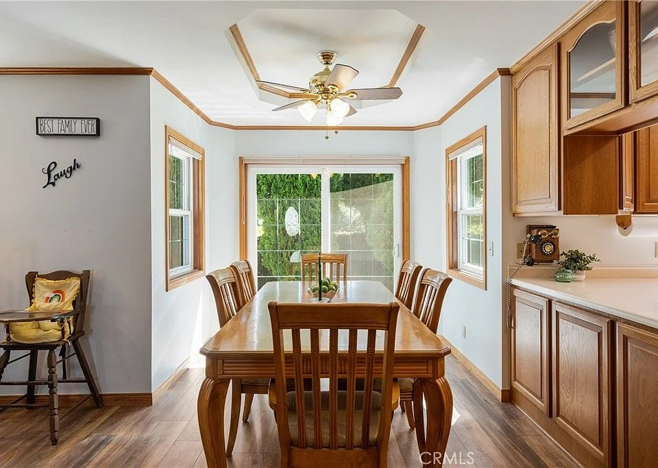 Dining area with wooden table and chairs, ceiling fan, and large windows