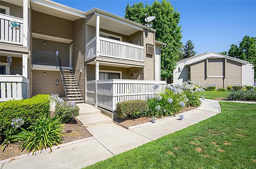 Two-story apartment building real estate with balconies, stairs, and garden plants.