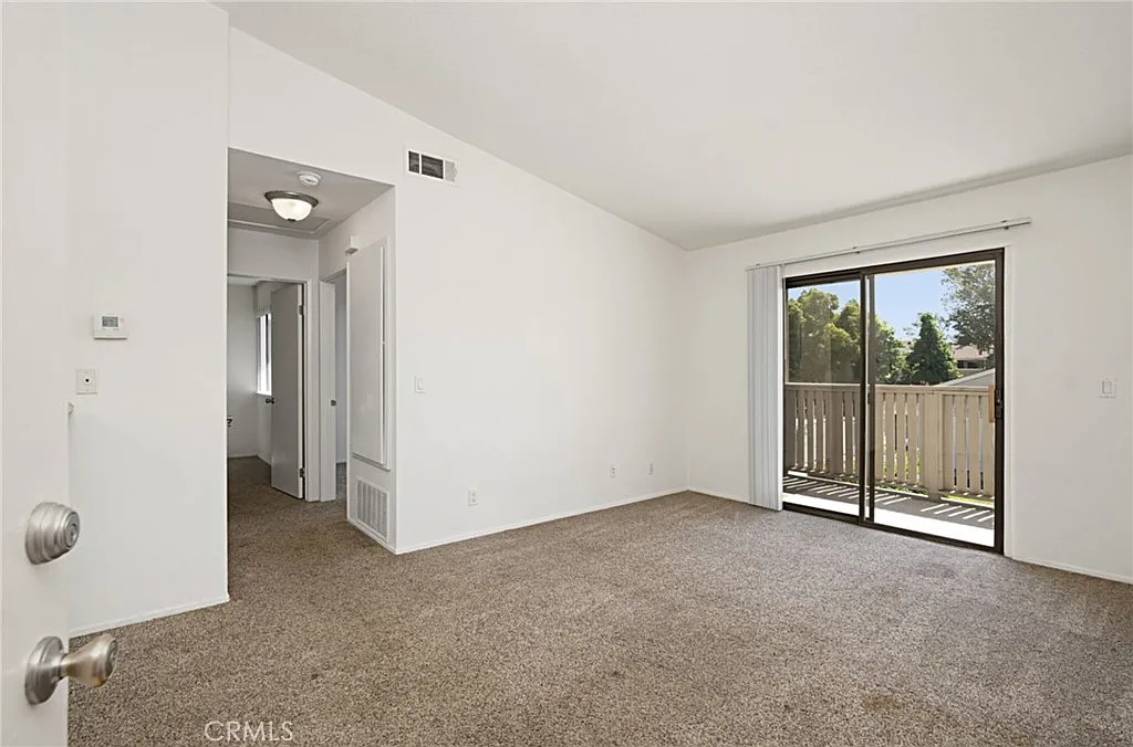 Entryway with white door on gray exterior wall, small welcome mat, and angled roof above, real estate.
