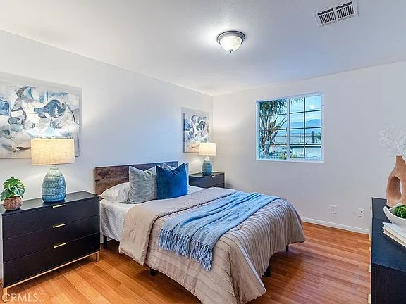 bedroom with bed, bedside lamps, plant, and window light
