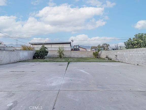 Open concrete area with low walls and greenery in the background