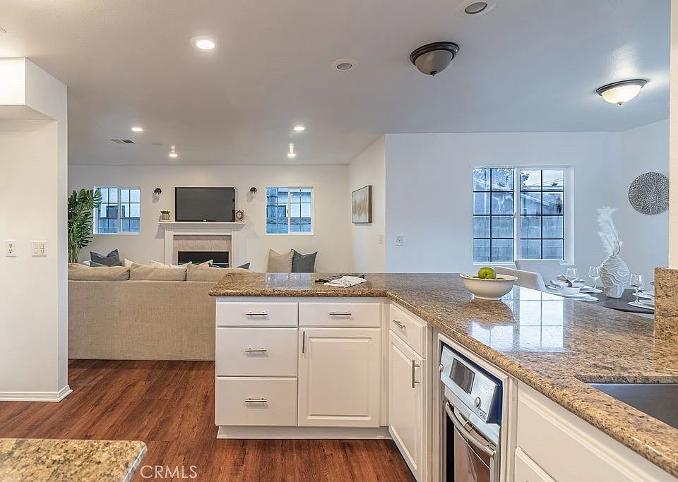 kitchen with granite countertops, white cabinets, stainless steel appliances, and view of living room with fireplace and windows