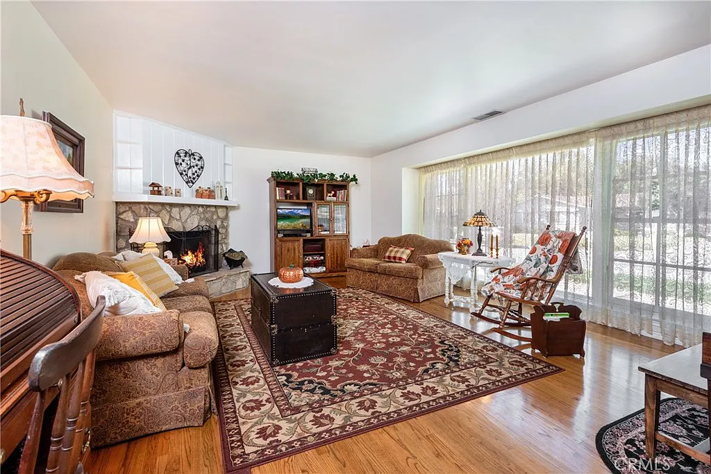 Cozy living room with two sofas, rocking chair, coffee table, fireplace, and patterned rug