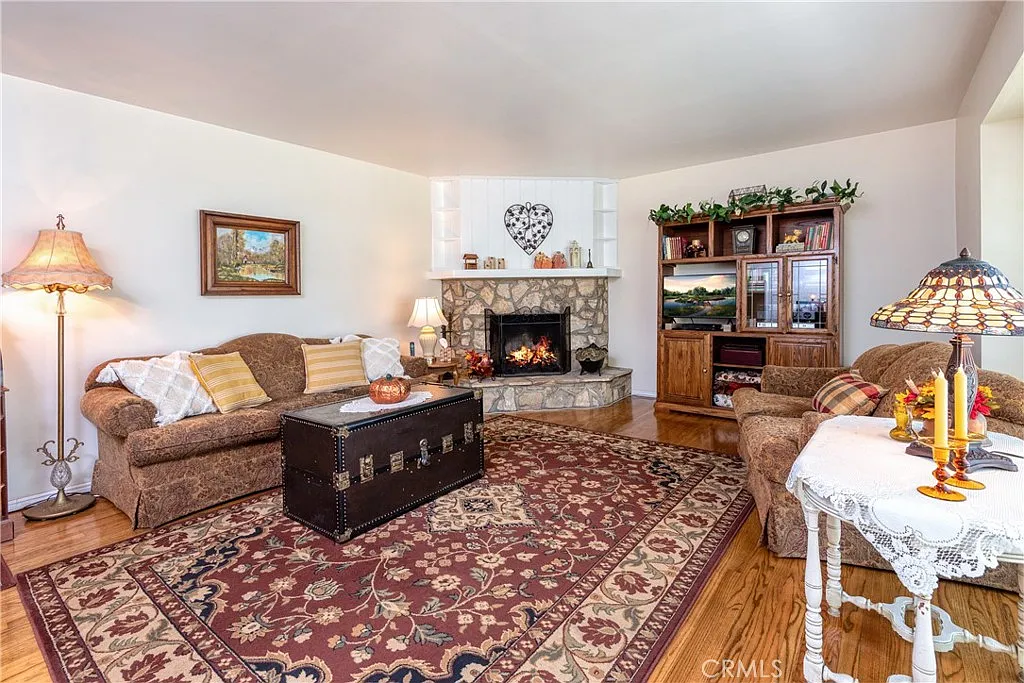 living room with stone fireplace, sofa with cushions, decorative rug, and coffee table with candles