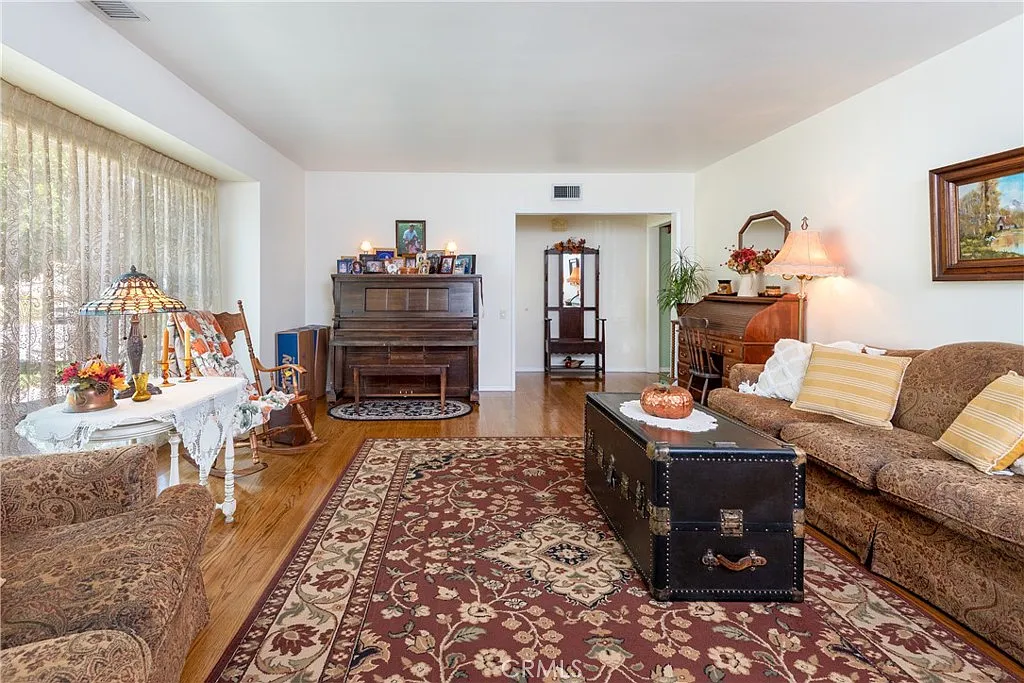 Living room with patterned rug, two sofas, coffee table, and wooden piano