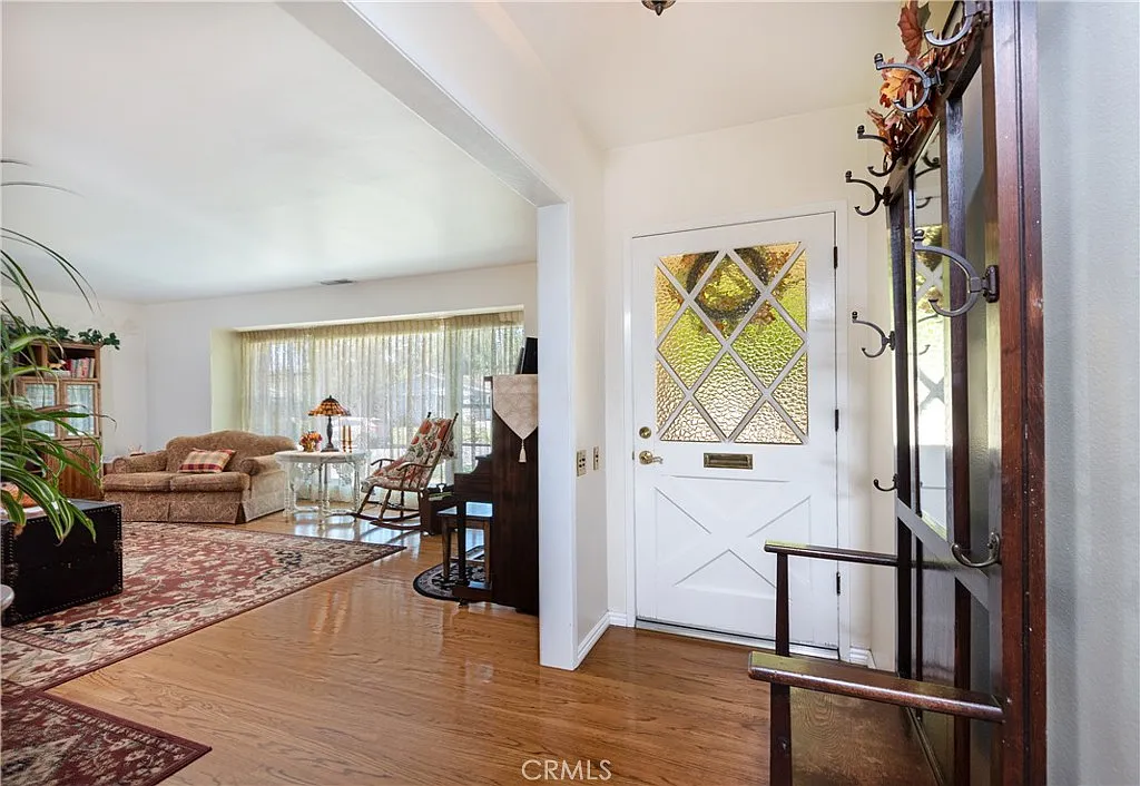 Interior entrance with diamond glass door, wooden floor, and living area with couch and lamp