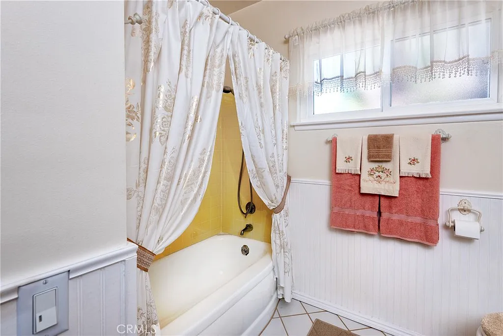 Bathroom with bathtub, shower curtain, yellow walls, and decorative towels