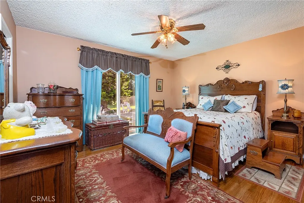 bedroom with wooden bed, decorative bedding, dresser, chair, and blue-curtained window