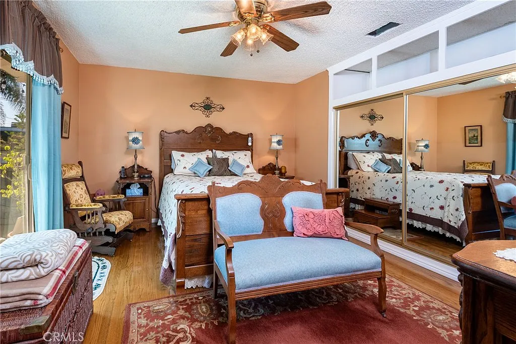 bedroom with wooden bed, floral bedding, mirrored closet, armchair, and small bedside table