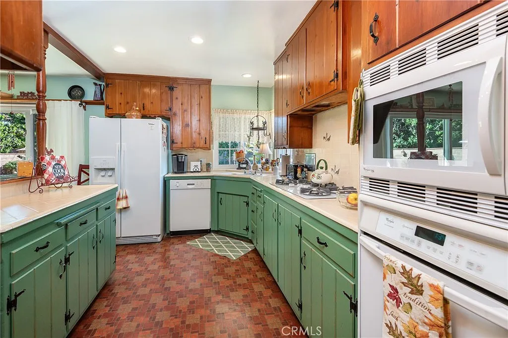 Kitchen with green cabinets, white refrigerator, appliances, and brown tile floor