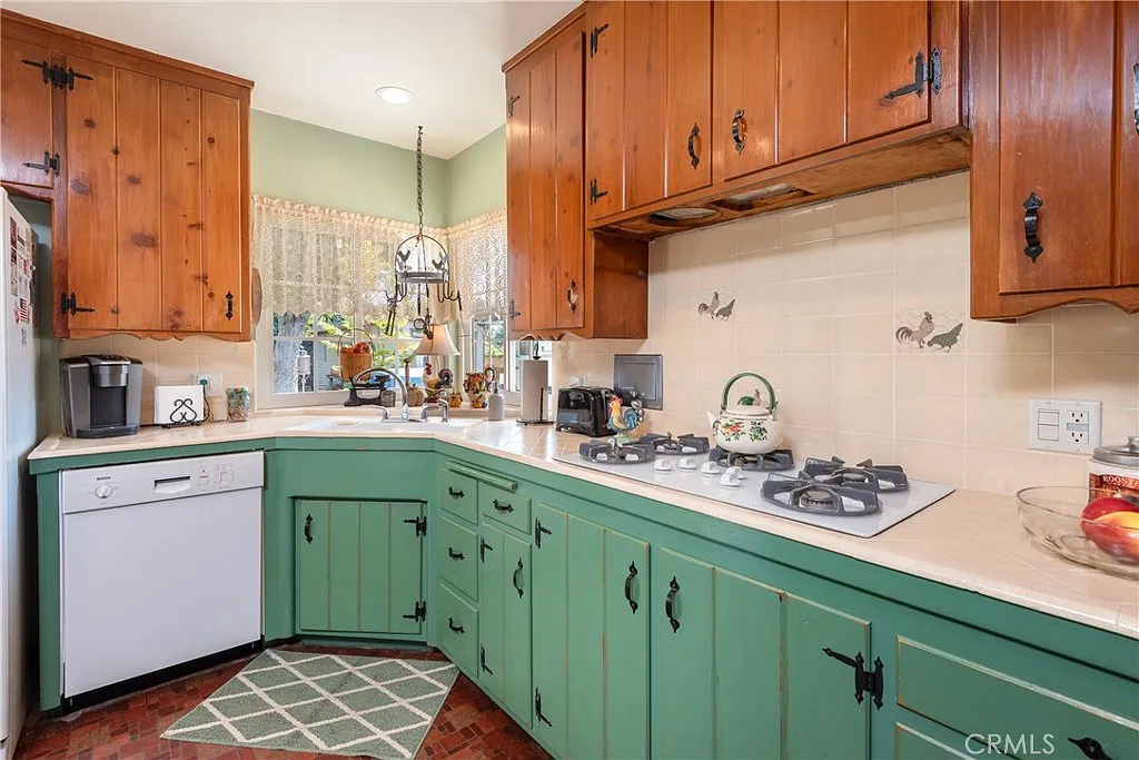 Kitchen with wooden and green cabinets, gas stove, dishwasher, and floral decor
