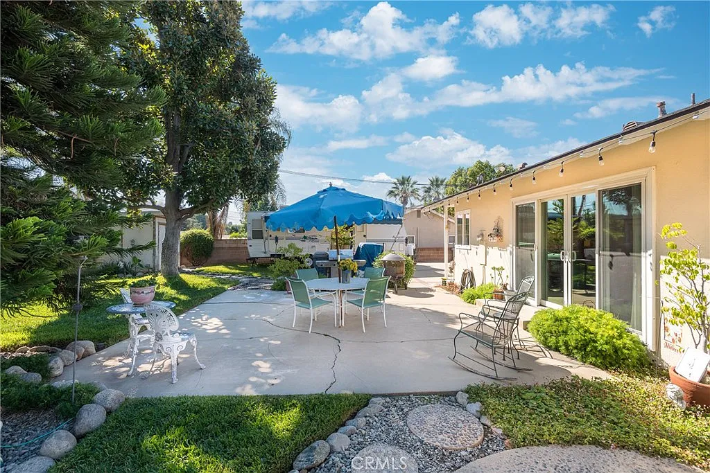 Outdoor patio with blue umbrella, chairs, tables, and surrounding trees