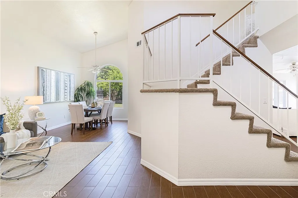 bright interior with staircase, dining area, and large windows.
