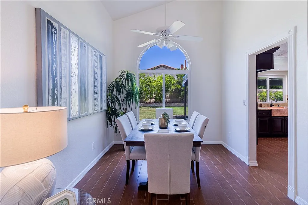 Dining area with table for six, large window with greenery view, and light-colored walls.