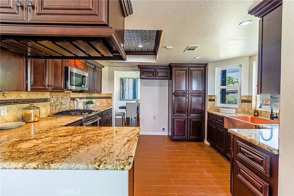 kitchen with dark wood cabinets, granite countertops, stainless steel appliances, central island, and view of dining area.