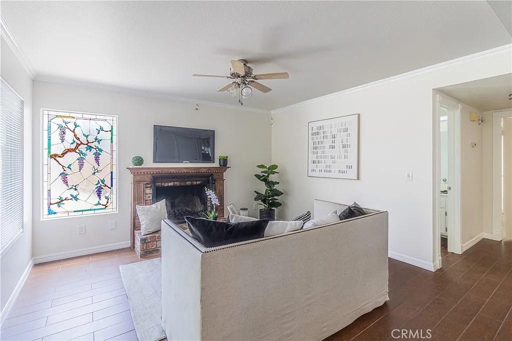 Living room with stained glass window, wall-mounted TV, fireplace, and white sofa with black pillows.